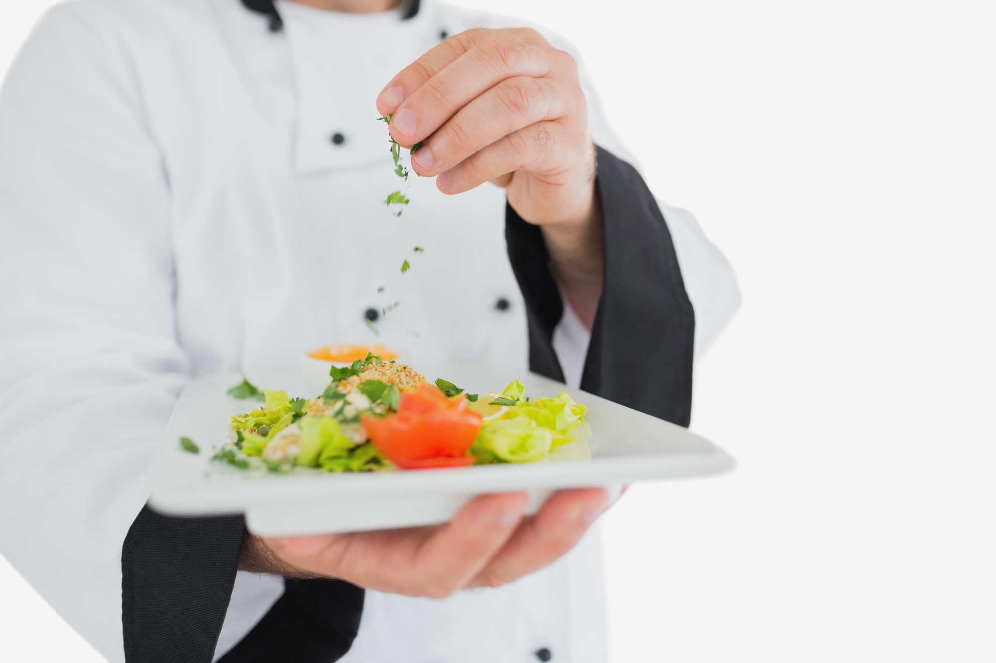 Chef arranging a plated seasonal dish in a modern kitchen